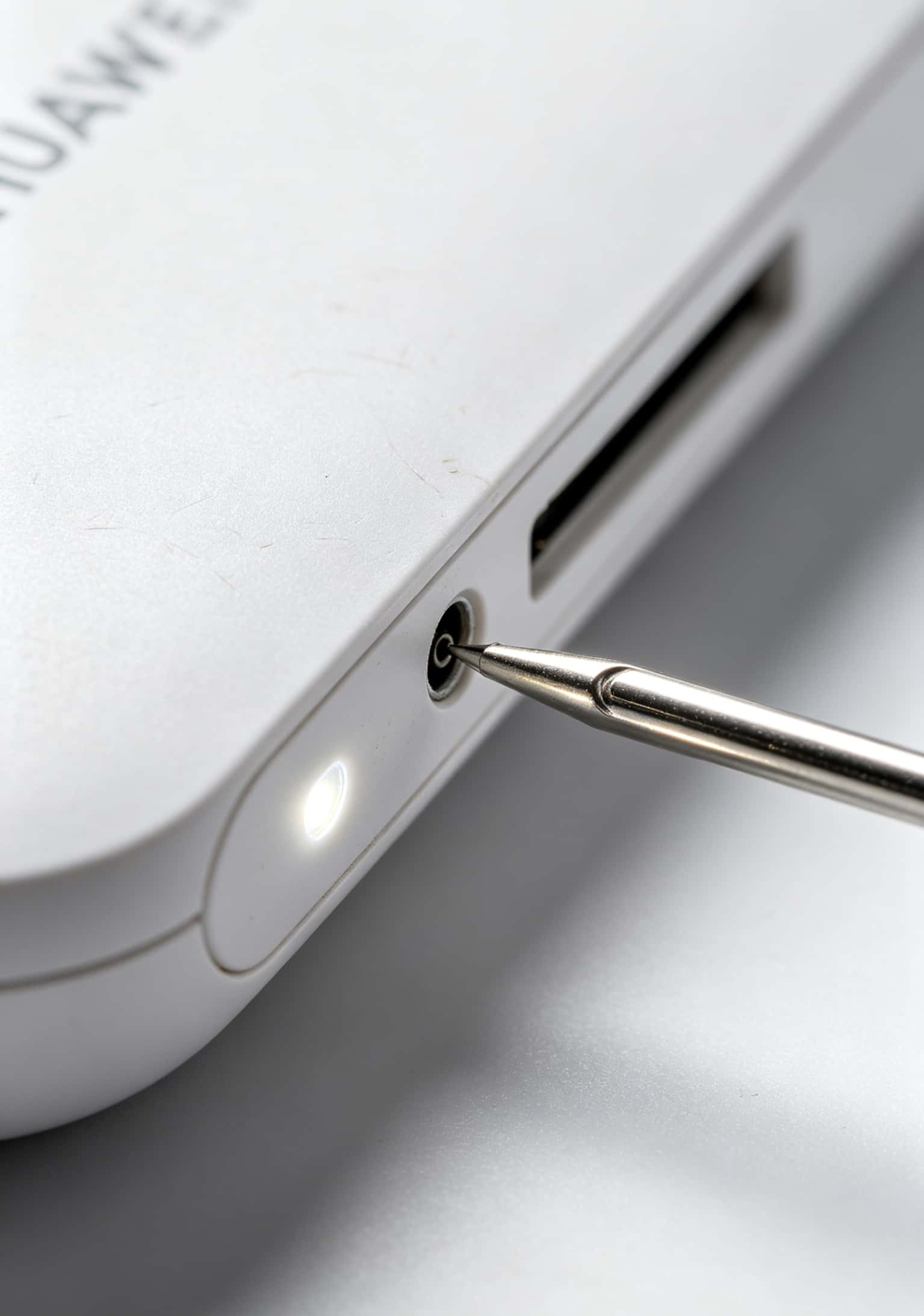 华为5G随身WiFi侧面的复位孔位置特写，用卡针指示
